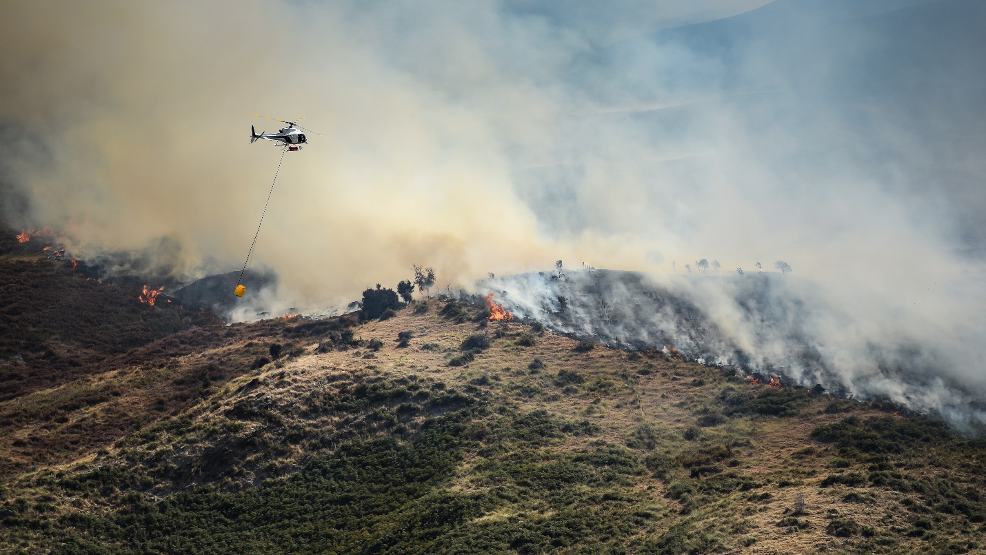 Firefighting helicopter with bucket drop water on forest fire