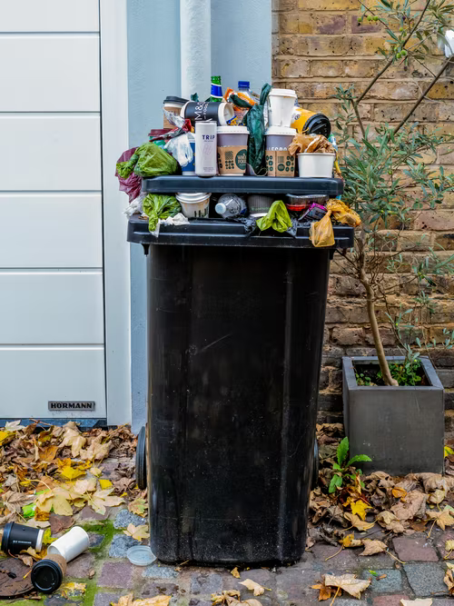 Overflowing black garbage can