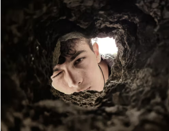 Young man looking inside a rodent hideout