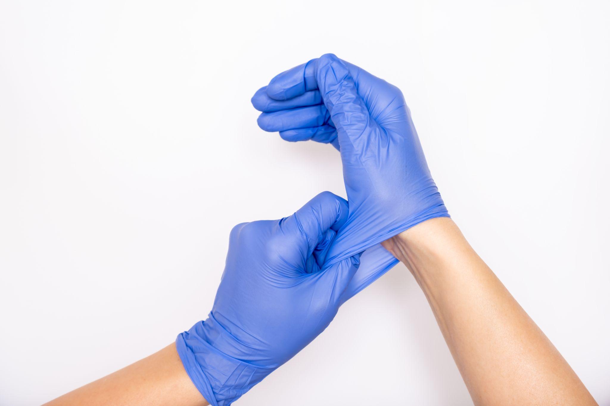 nurse putting on blue nitrile surgical gloves