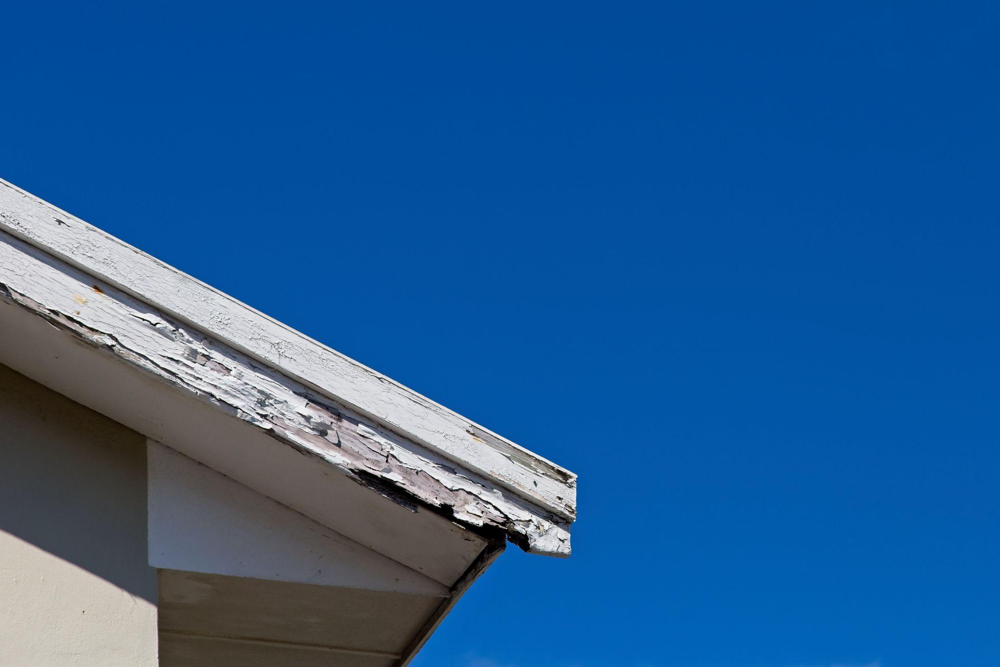 old rotting fascia boards and a blue sky background. 